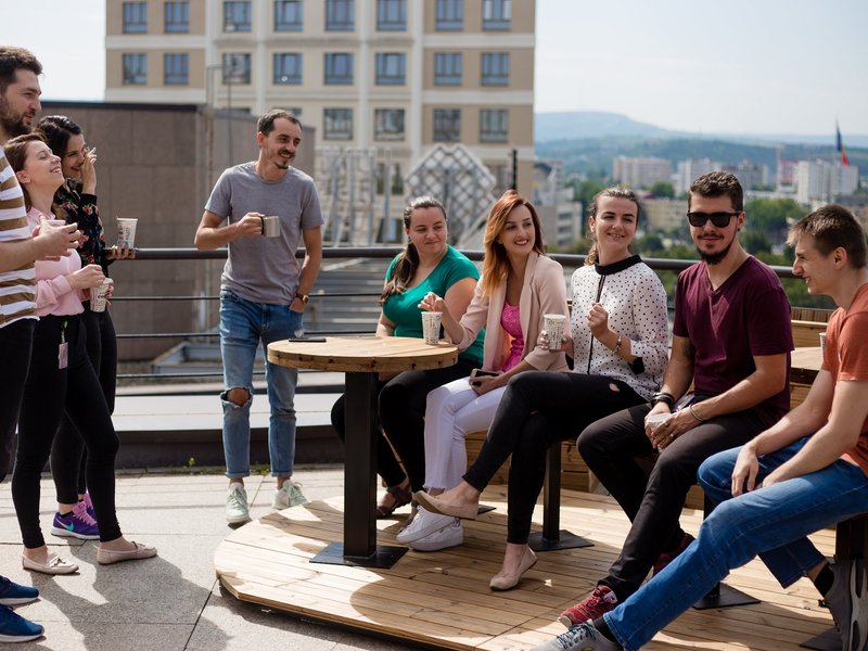 Team of software testers and developers having coffee together on the terrace