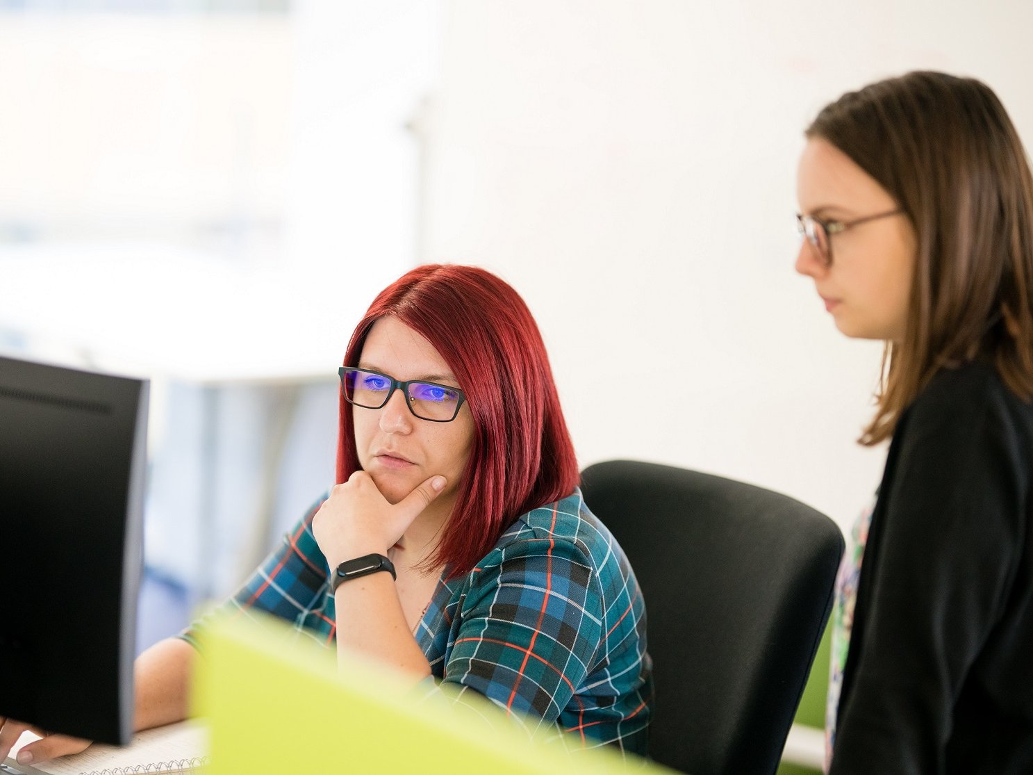 Two UI UX designers looking at a computer discussing an issue