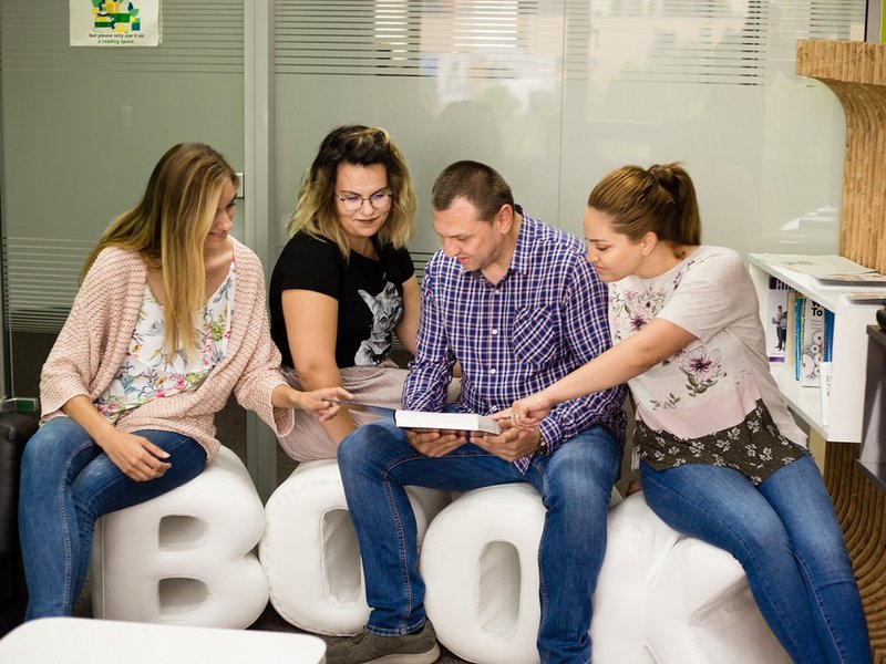Software testers, full stack developers, and net developers sitting in the library reading a book