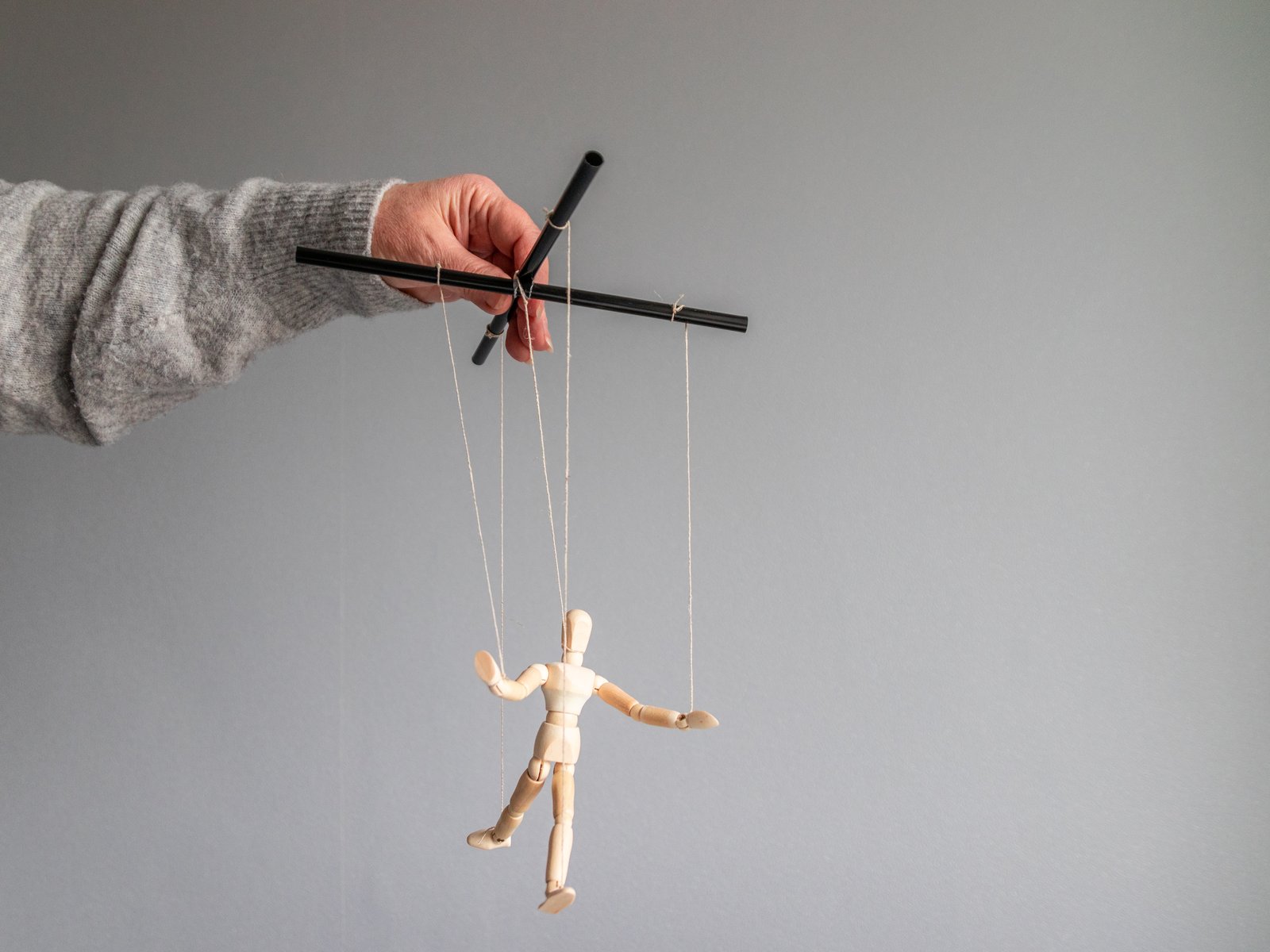 human-hand-holds-wooden-doll-clothesline-gray-background-with-place-text-power-metaphor-concept