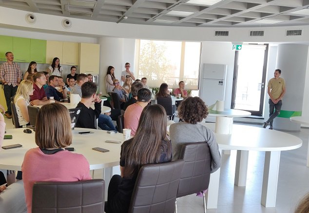 Interns, students, mentors, software developers, and QA software testers sitting together during a presentation demo during the internship program