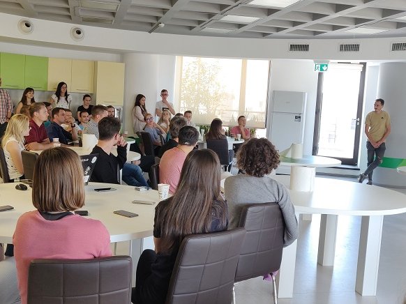 Interns, students, mentors, software developers, and QA software testers sitting together during a presentation demo during the internship program