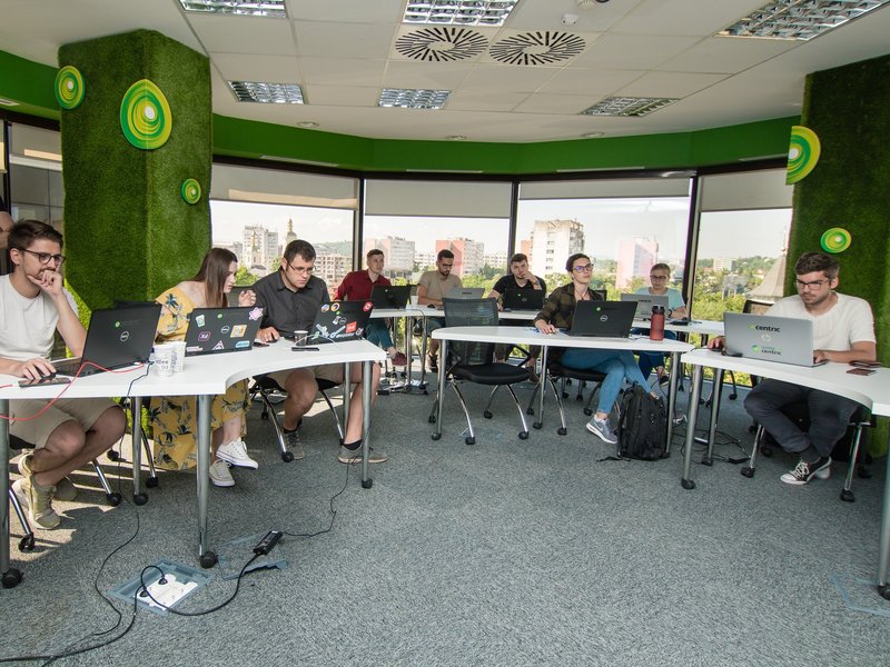 Software developers and QA software testers sitting at tables, working on laptops during a training course