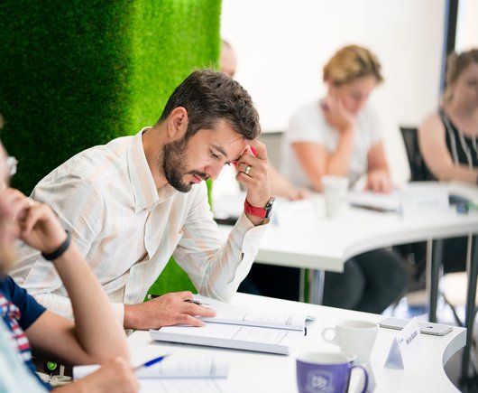 student sitting at a table reading a book during a course